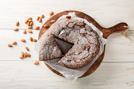 Torta caprese is a flourless chocolate cake made with almonds closeup on the wooden board on the table. Horizontal top view from above
