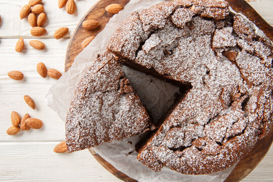 Italian Torta Caprese is a decadent, flourless cake made with dark chocolate and almonds closeup on the wooden board on the table. Horizontal top view from above