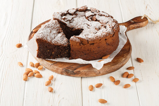 Italian Torta Caprese is a decadent, flourless cake made with dark chocolate and almonds closeup on the wooden board on the table. Horizontal