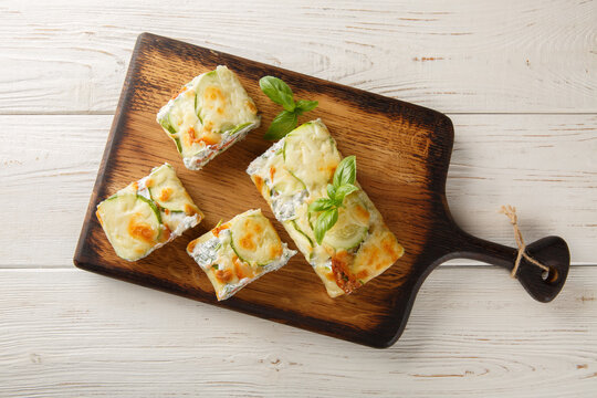baked zucchini roll with cheese, stuffed with salmon and cream cheese, on a wooden board on the table. Horizontal top view from above