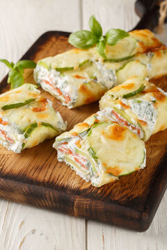 Zucchini roll with cream cheese and salmon closeup on the wooden board on the table. Vertical