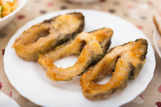 three pieces of fried carp on a white plate
