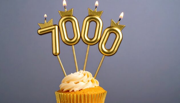 Close-up of a festive cupcake with lit golden 7000 number candles, celebrating a birthday, anniversary, or significant achievement on a gray background.