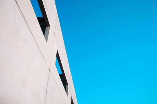 Concrete building with large windows open to the outside and a blue-green sky.