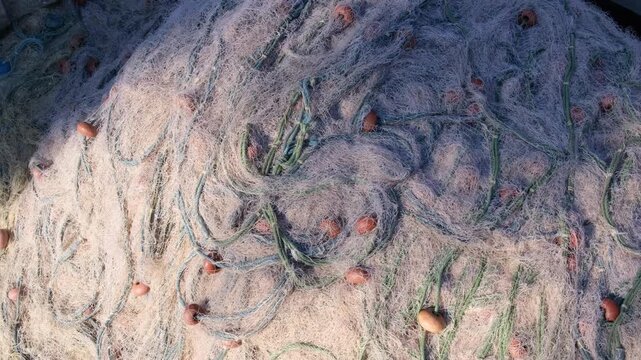 Detailed top view of a large pile of tangled fishing nets with floats drying in the sun ,fa01