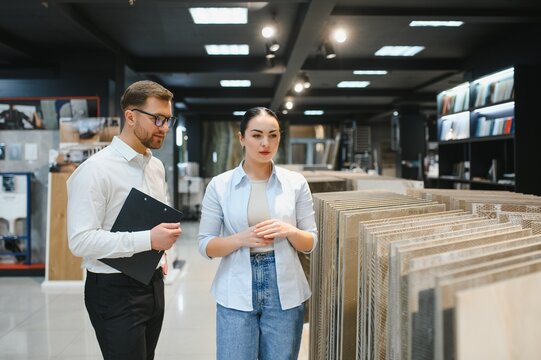 Shop assistant showing ceramic tiles to woman in hardware store