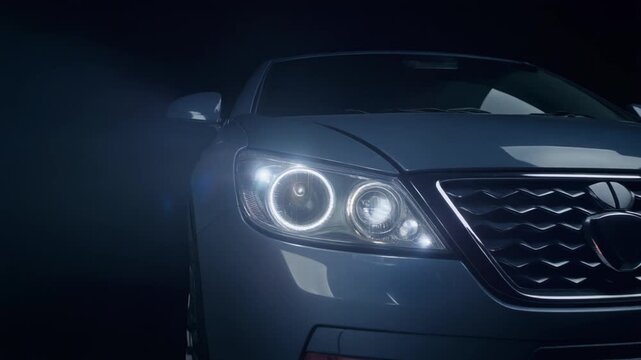 深い闇から現れる自動車のフロントグリルとLEDヘッドライト、ローアングルのスローリビール