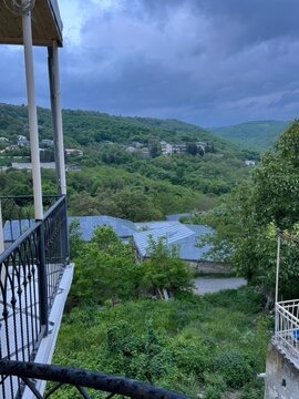 Mountain valley landscape with dramatic storm clouds over green forest and rural village countryside