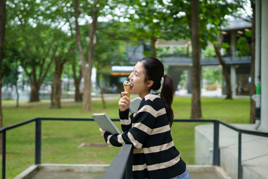 University student, young woman college student eating ice cream standing in campus building, The relaxed atmosphere highlights a casual break after a day of classes