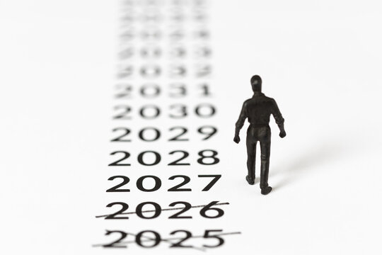 miniature man walking towards new year 2027 leaving crossed out past years behind