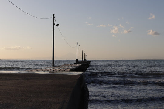 Wooden breakwater jetty stretching into a calm sea at dusk