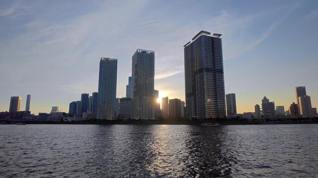 高層ビルの間に沈む夕陽が見える運河の風景。