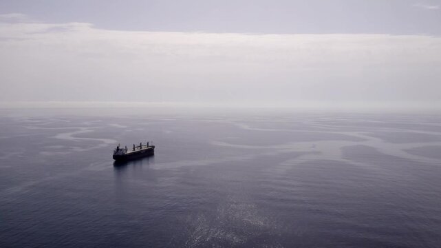 Aerial drone view of a bulk carrier cargo ship sailing on the calm Mediterranean sea in hazy weather on its trade route