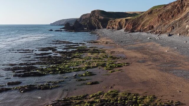 Drone view flying backwards evening light at Sandymouth Bay in Cornwall