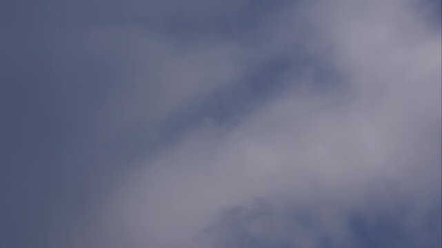 Gray clouds slowly drifting across a blue sky in timelapse with no land visible. Calm atmosphere.