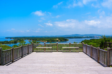 Obraz premium Spacious wooden deck terrace and benches at Kirigaki Observatory in Tomoyama Park. The calm islands of Ago Bay unfold beyond the railing, offering an open and serene travel atmosphere.