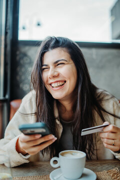 Happy woman buying online using smartphone and credit card