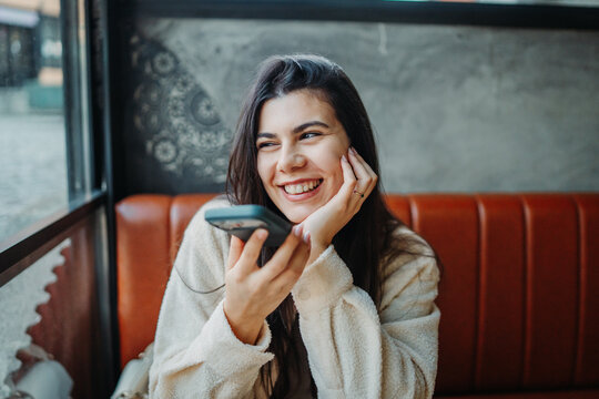 Woman sending voice message with smartphone in cafe