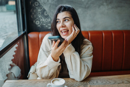 Woman sending voice message in a cafe