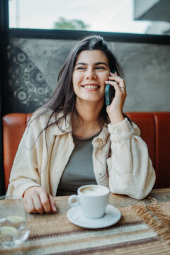 Smiling woman talking on phone and drinking coffee