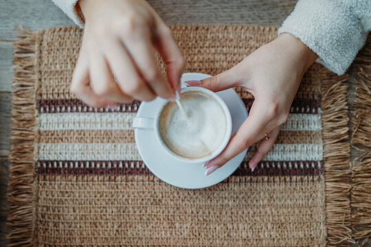 Female hands stirring coffee in white cup