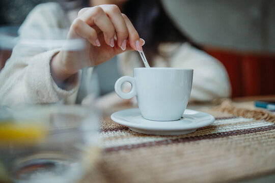 Woman stirring cup of coffee enjoying morning drink