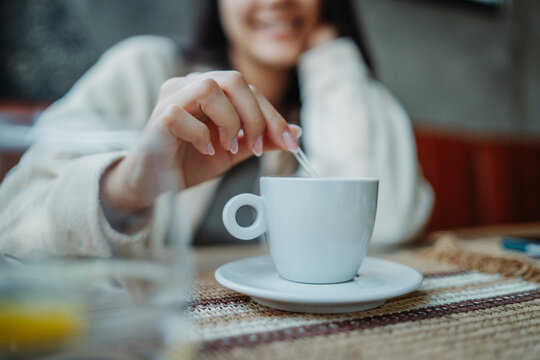 Woman stirring hot coffee cup in a cafe