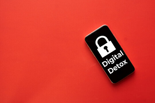 Digital detox and technology addiction concept. A smartphone displaying a padlock icon and Digital Detox text on a vibrant red background with copy space for mental health awareness.