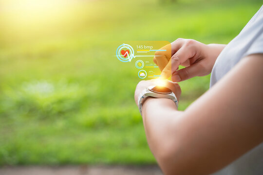 The young woman monitors her heart rate via an application on her smartwatch. The concept involves exercising for health, such as running and walking.