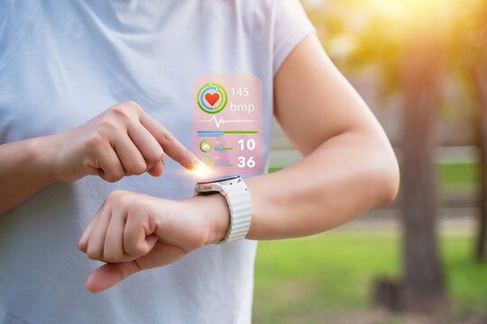 The young woman monitors her heart rate via an application on her smartwatch. The concept involves exercising for health, such as running and walking.