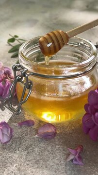 Acacia honey dripping from dipper into jar