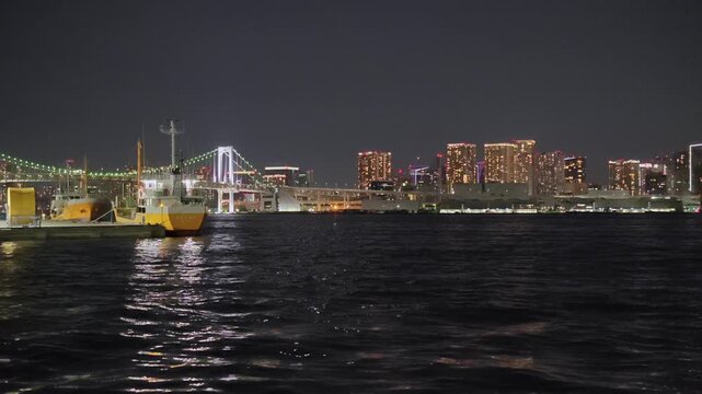 橋と船と高層ビルが見える港の夜景。