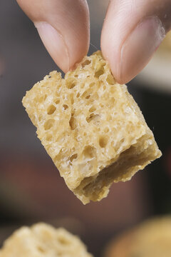 Fresh Golden Honeycomb Piece Held in Hand Showing Natural Hexagonal Structure and Dripping Honey