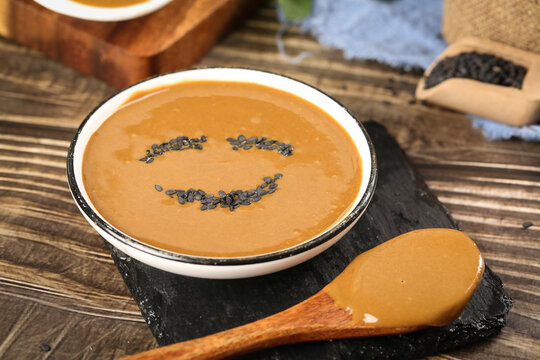 Pure sesame sauce with smiley face design - traditional Asian dipping sauce in bowl with wooden spoon