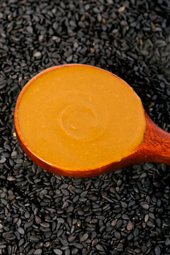 Hot Sesame Sauce in Wooden Spoon on Black Sesame Seeds - Traditional Henan Condiment