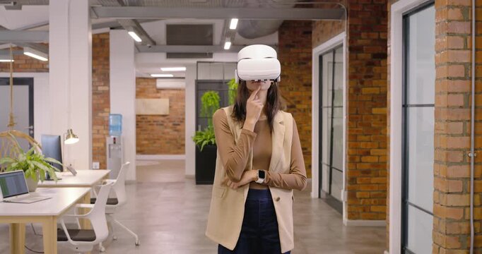African American woman responding to VR prompt, tapping headset and checking watch at office