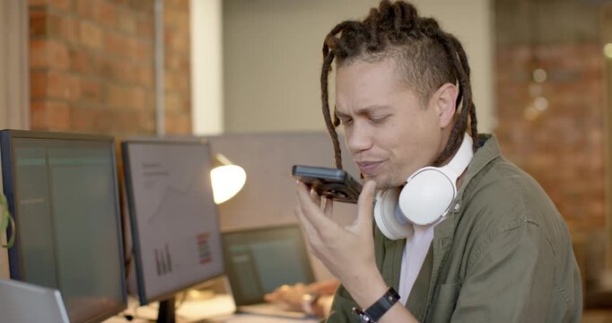 African American man in olive shirt seeing phone picking it talking for update returning to laptop