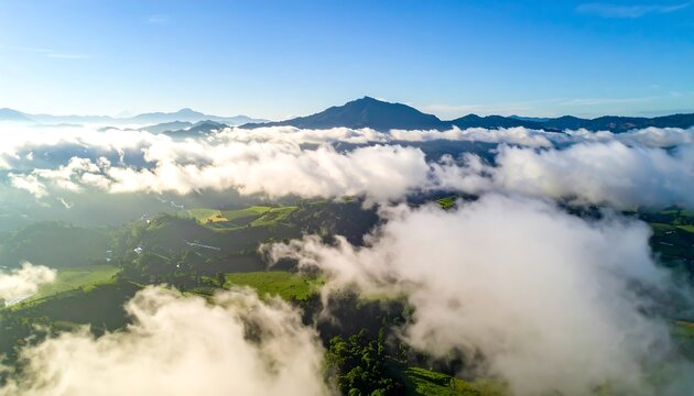Aerial view of lush green landscape with fluffy white clouds and distant mountains under blue sky