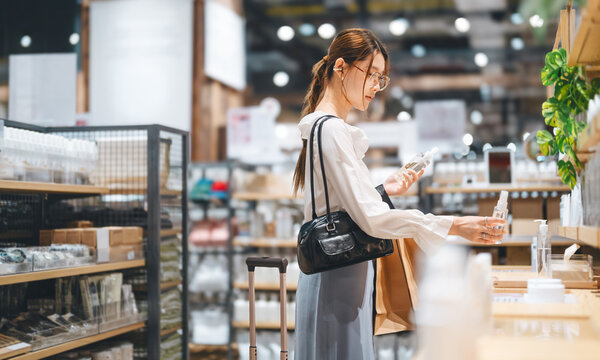 Young adult asian woman shopping facial skin care choosing beauty product in retail store japanese business look fashion