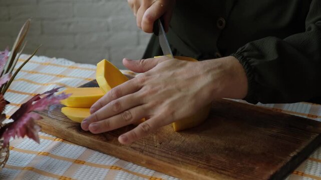 Hands slicing pumpkin. Preparing autumn food. Cooking pumpkin soup or cake.