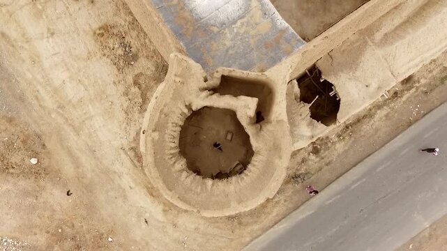 Spectacular top-down aerial viewpoint looking directly down onto an old mud castle ruins and clay fortress structures in a quiet desert village layout, revealing authentic earth textures.