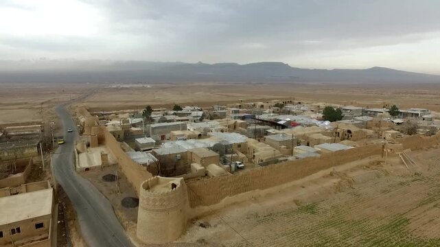 Breathtaking aerial view displaying the immense scale of an old clay fortress and ancient mud castle structure nestled in a remote desert village settlement, perfect for heritage video assets.