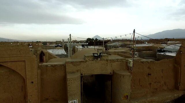 Fascinating wide-angle uav flight tracking an old mud castle wall and historic clay fortress tower inside a remote desert village settlement, highlighting traditional lifestyle sceneries.