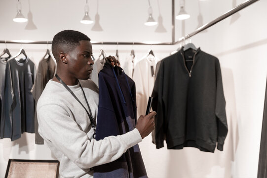 Male shopper comparing navy blazer in contemporary menswear store with hanging garments