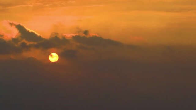 A dramatic view of a sunset, where thick dark clouds mask the sun. Warm orange light bursts through, framing the cloud edges with a brilliant silver lining that symbolizes hope in darkness. Timelapse
