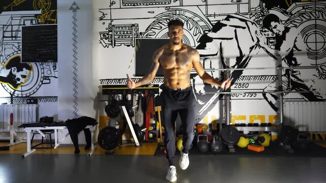 Muscular afro american sportsman skipping with a jump rope at sport club. Strong african athlete with tattoos exercising at modern gym. Young black sporty man doing cardio in fitness centre. Close up