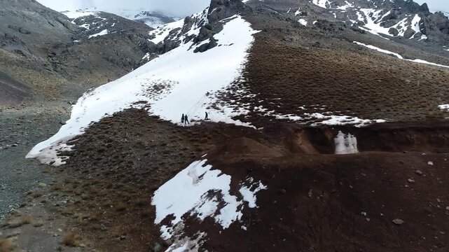 Beautiful low altitude drone view tracking near a narrow dirt path along a snowy mountain side, revealing cold winter travel conditions and remote alpine wilderness scenery item world.