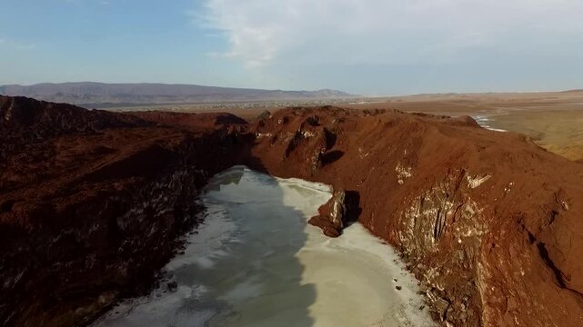 High-altitude drone capture of an ancient salt dome structure with an embedded turquoise pond and sharp crimson ridges, highlighting the raw power of natural erosion and land formation online.