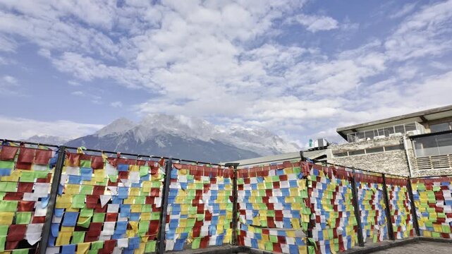 Colorful Tibetan Prayer Flags Hanging In Front Of Snow-Capped Mountain Under Cloudy Blue Sky