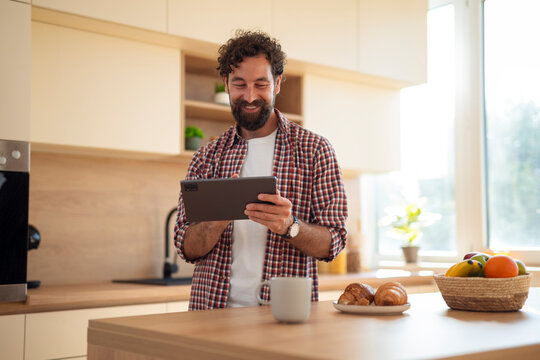 Man enjoying morning using digital tablet in kitchen